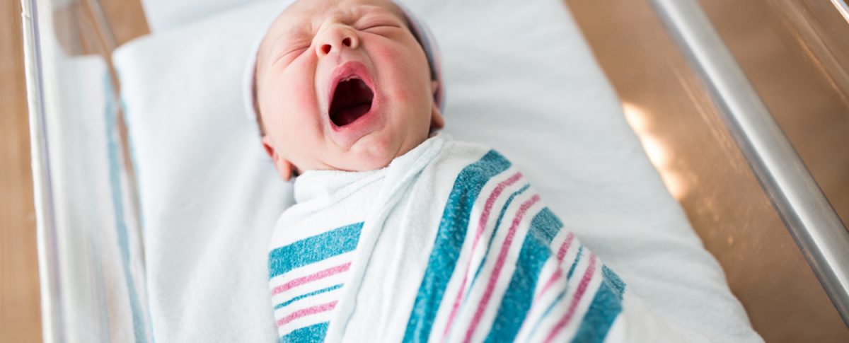 A swaddled newborn yawning