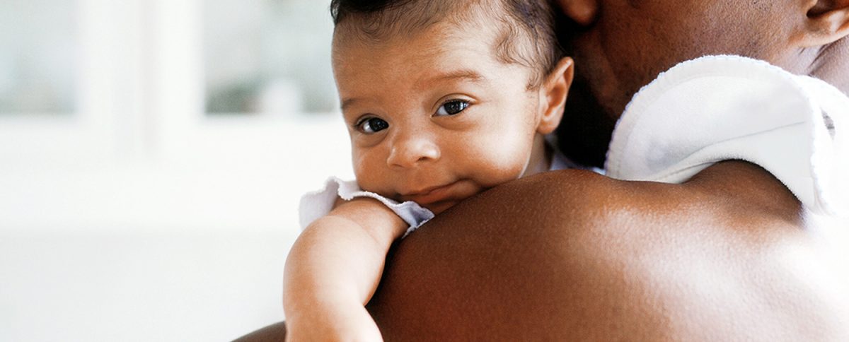 A woman holding a baby over their shoulder.