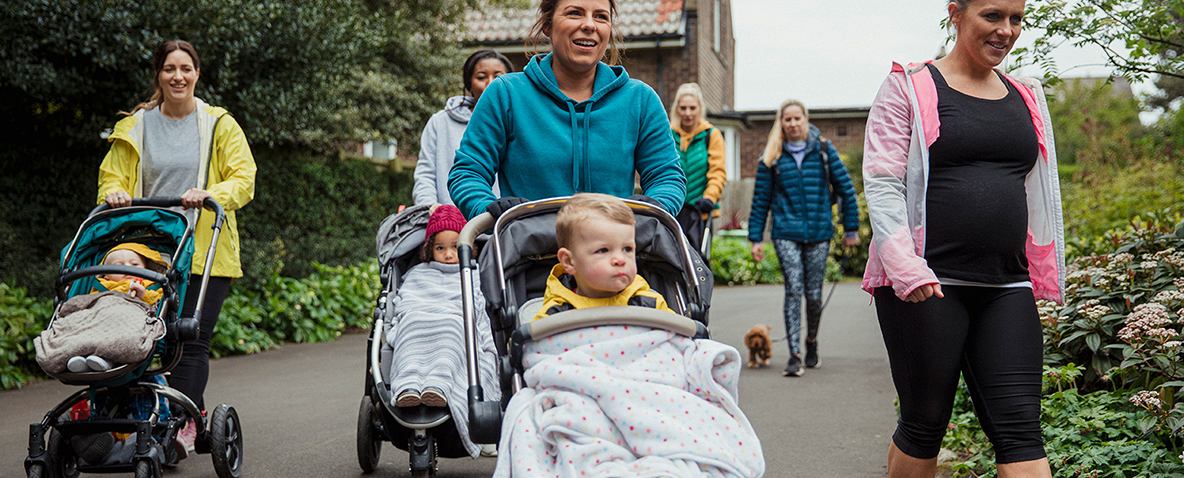 A pack of mothers walking with their children in strollers