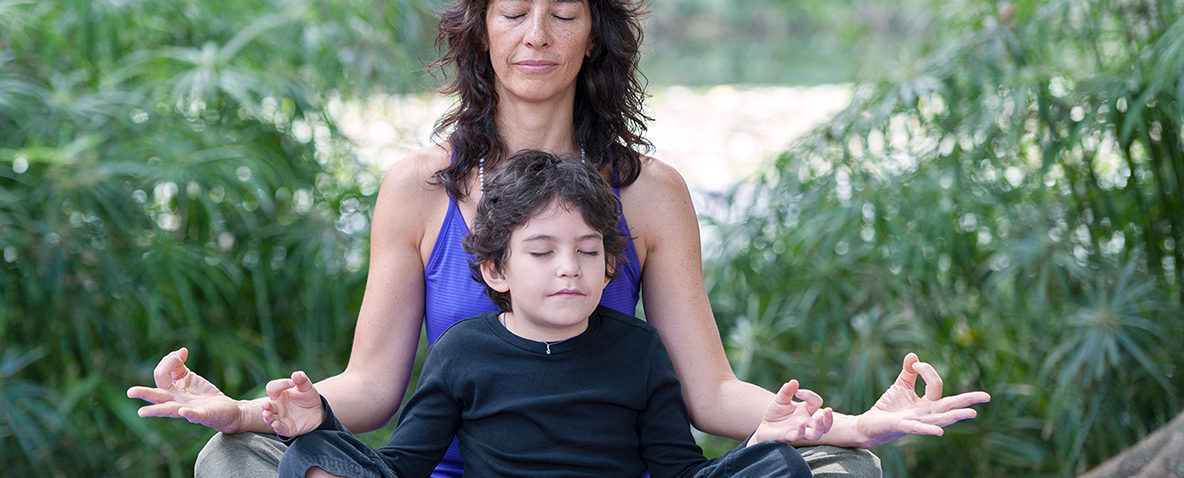 A mother and child meditating together in a park